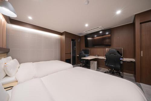a bedroom with two beds and a desk and a computer at Brown Dot Hotel Sangju in Sangju
