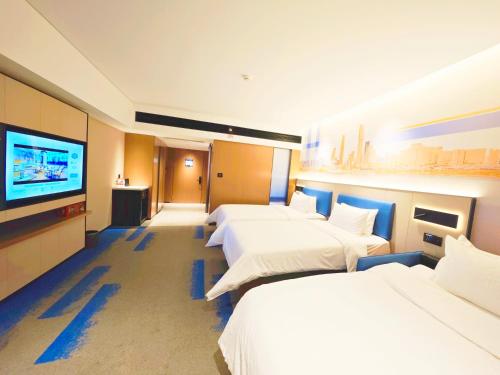 a hotel room with three beds and a flat screen tv at Hampton by Hilton Guangzhou Railway Station in Guangzhou
