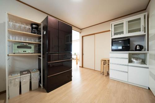 a kitchen with a black refrigerator and white cabinets at Lilac in Sapporo