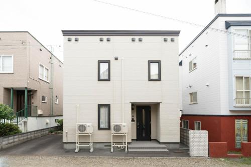 a white house with two chairs in front of it at Lilac in Sapporo