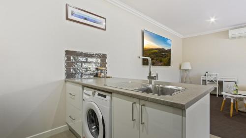 a kitchen with a sink and a washing machine at The Metung Crest in Metung