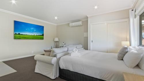 a white bedroom with a large bed and a couch at The Metung Crest in Metung
