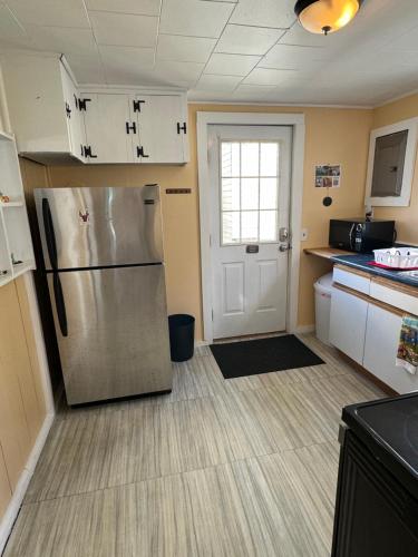 a kitchen with a stainless steel refrigerator and a door at Beach Cottage on North Beach in Hampton