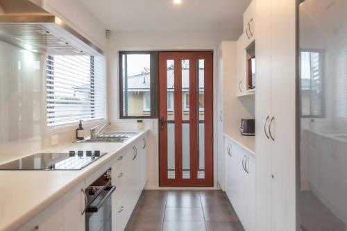 a kitchen with white counters and a red door at Stylish Central City Apartment on Bealey in Christchurch
