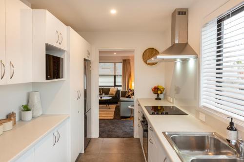 a kitchen with white cabinets and a sink at Stylish Central City Apartment on Bealey in Christchurch