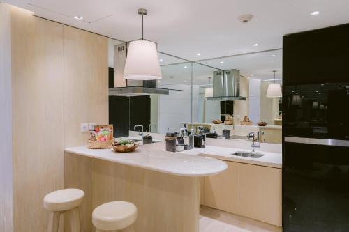 a kitchen with a sink and a counter with stools at COMO Uma Canggu in Canggu