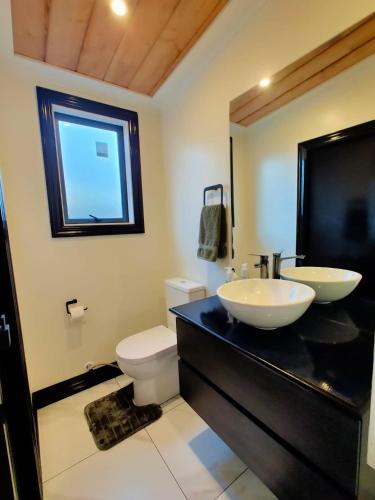 a bathroom with two sinks and a toilet at A Stone's Throw From Town Tiny Home in Dunedin