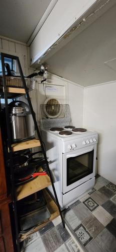 a small kitchen with a stove and a shelf at Meyenburg Dorm Room in Mount Morgan
