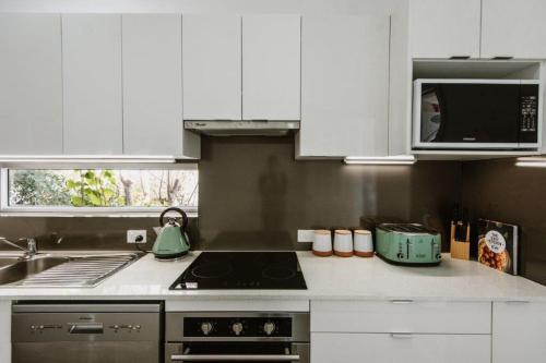 a kitchen with white cabinets and a stove top oven at City Sider Motel in Tamworth