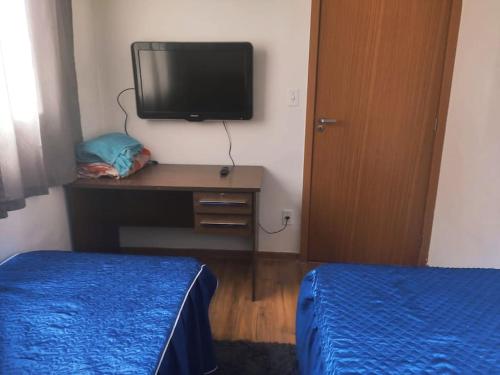 una camera con letto e scrivania con TV di apartamento no paraiso a Ponte Nova
