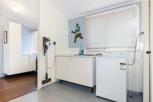 una cucina bianca con lavandino e finestra di Park Rise Cottage a Busselton