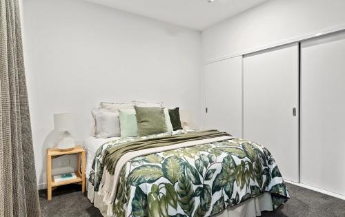 a white bedroom with a bed with a tropical bedspread at Central & Chic in the Capital in Wellington