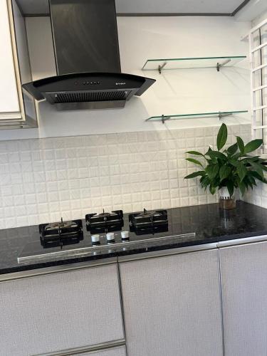 a kitchen with a stove top with a black hood at MJ Esperanza in Cochin