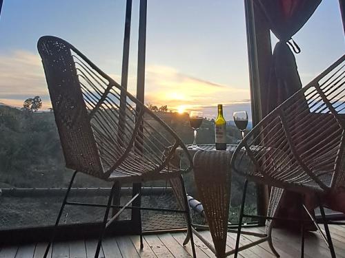 two chairs and a table with wine glasses on a balcony at Chalet de Liz - Guatapé in Guatapé