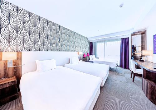 a white hotel room with a bed and a desk at Mercure Okinawa Naha in Naha