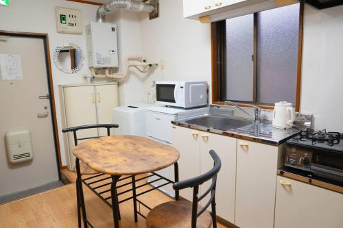 a kitchen with a table and two chairs and a microwave at 2階 小岩駅徒歩15分 収容4人 成田羽田からバス直通 in Tokyo