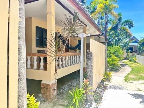 a house with a fence and palm trees at Ibiza Bungalows in Haad Yao