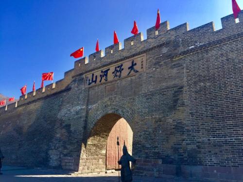 张家口Nostalgia Hotel Zhangjiakou- Near The Grass Skyline, Dajingmen, 20 minutes away from Zhangjiakou High-speed Railway Station, Free ice cream, mineral water, coffee, snacks and laundry service, English communication well的站在砖墙前,有城堡的人