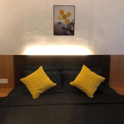 a black couch with two yellow pillows on it at Nu Melati Hotel in Pantai Cenang