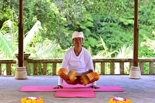 a man is sitting on a pink yoga mat at Bagus Jati Health & Wellbeing Retreat in Tegalalang
