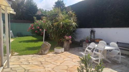 a patio with chairs and a table and a tree at App ensoleillé Guéthary classé 2 * avec terrasse et jardin privatifs in Guéthary