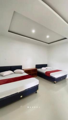 two beds in a room with a ceiling at Rinjani 3 Homestay in Cikembulan