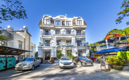 un edificio bianco con auto parcheggiate di fronte di TP Dalat Hotel a Da Lat