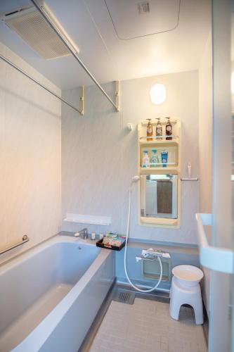 a bathroom with a tub and a toilet and a sink at 旅館依山盡イサンジン in Maniwa