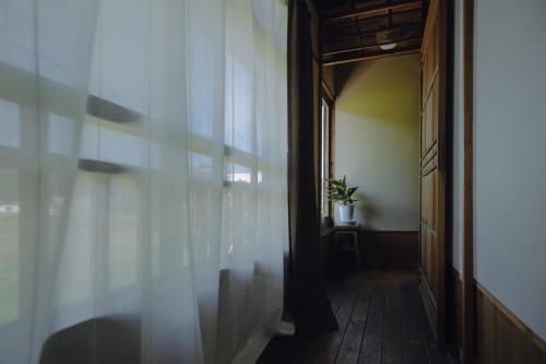 a hallway with a door and a potted plant at 旅館依山盡イサンジン in Maniwa