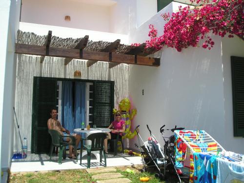 two people sitting at a table outside of a house at Apartamentos Las Brisas I & II in Cala'n Bosch