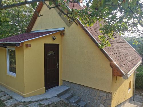 a yellow building with a door and a tree at Oxigén Apartman Igal in Igal