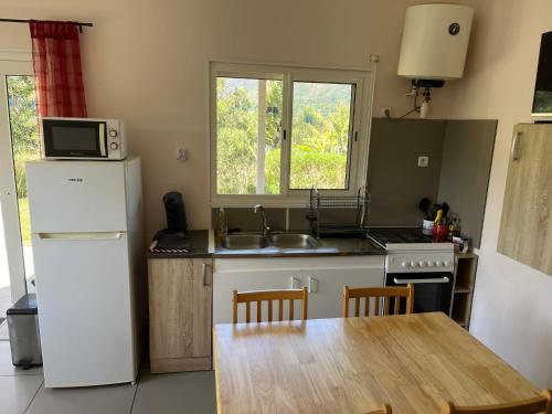 a kitchen with a wooden table and a white refrigerator at Gite Le Panoramique in Dumbéa