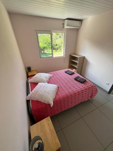 a small bedroom with a red bed and a window at Gite Le Panoramique in Dumbéa
