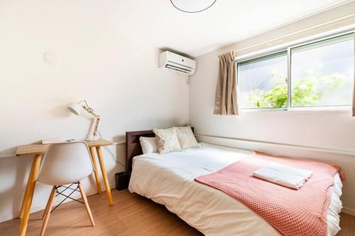 a bedroom with a bed and a desk and a window at 羽田5丁目 in Tokyo