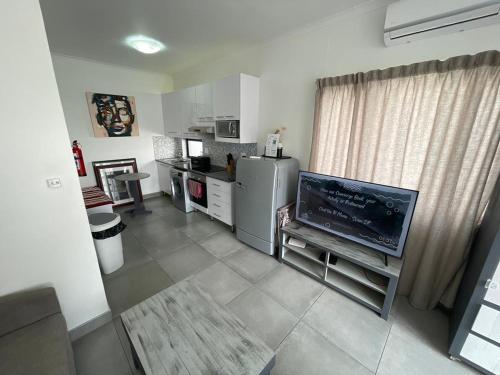a living room with a television and a kitchen at Fischreiher Seaside Self Catering Studio Apartment in Swakopmund