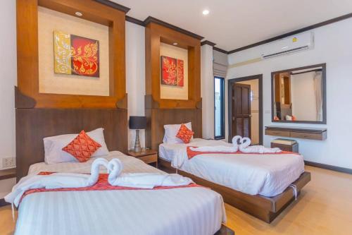 a hotel room with two beds with swans on them at Monica Villa 24 in Ban Chong Phli