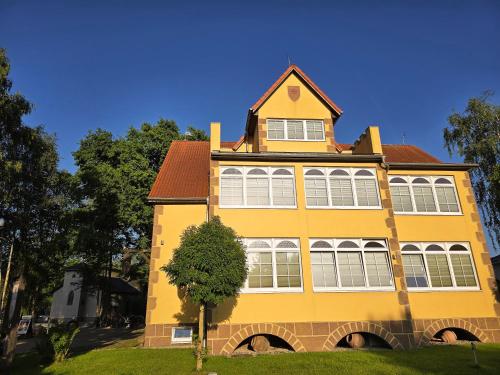 a yellow house with a tree in front of it at Ostsee-Rittergut-Rügen mit BinzHotel & OrdensKapelle & RomantikGut in Binz