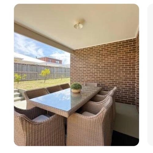 a patio with a table and chairs and a brick wall at Blue Breeze in Torquay
