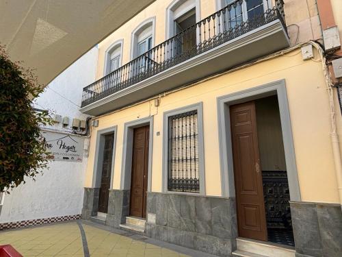 a building with two brown doors and a balcony at Patios de la Carmela in Isla Cristina