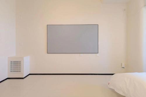 a white room with a bed and a white wall at Dream Inn Hotel Beijing in Beijing