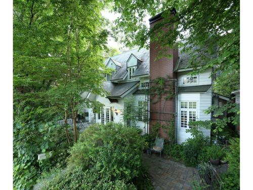 a large white house with a brick chimney at Country Inn Orchard House in Hokuto