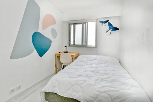 a white bedroom with a bed and a desk at Appartement front de mer - Terrasse in Pornichet