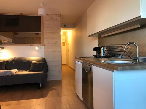 a kitchen with a sink and a couch in a room at Le Cocon d'Edwige - Vue montagne in Chamrousse