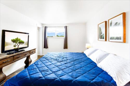 a bedroom with a blue bed and a television at High Dunes Condos in Ocean Shores