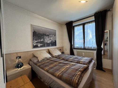 Un dormitorio con una cama y una ventana grande. en 018 Bilocale in centro, Pinzolo, en Pinzolo