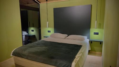 a bedroom with a large bed with green walls at Cozy Wooden House near Gudauri in Gudauri
