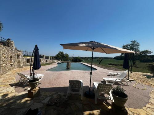 un patio avec un parasol et des chaises et une piscine dans l'établissement Gite 3, à Lauraët
