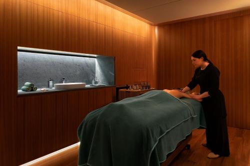 a woman is making a bed in a room at Sheraton Lake Como Hotel in Como