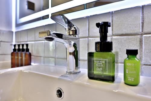 a bathroom sink with a bottle of soap and a soap dispenser at Wuzhen Residence B&B in Tongxiang