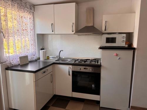 a kitchen with white cabinets and a stove and a sink at Apartman Žanić Crikvenica with Hot tub in Crikvenica
